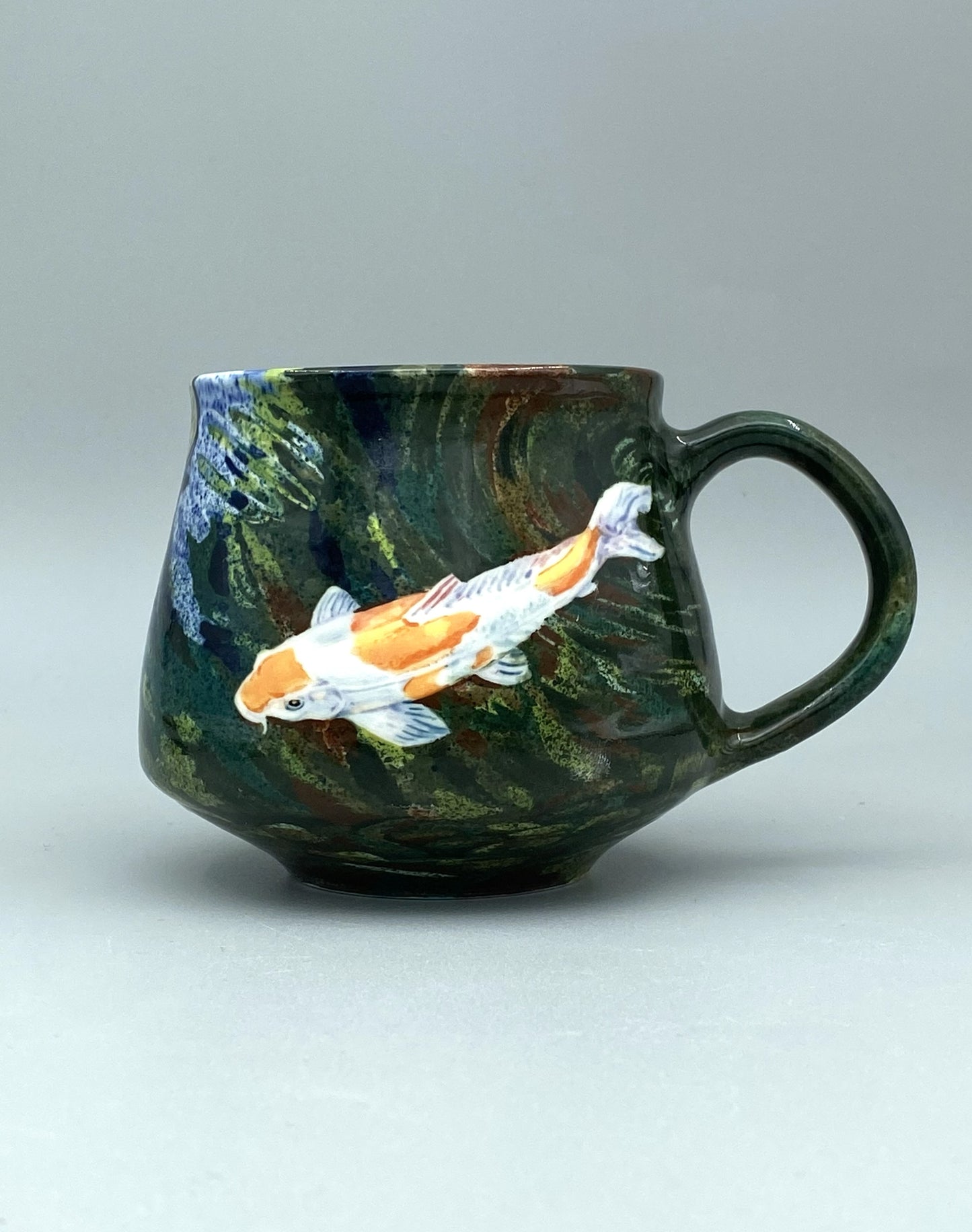 Ceramic mug with koi fish design on a gray background