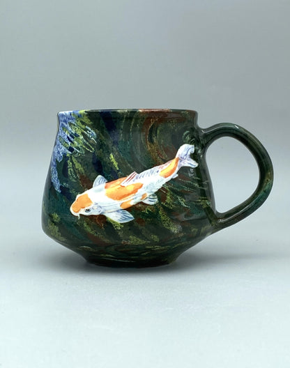 Ceramic mug with koi fish design on a gray background